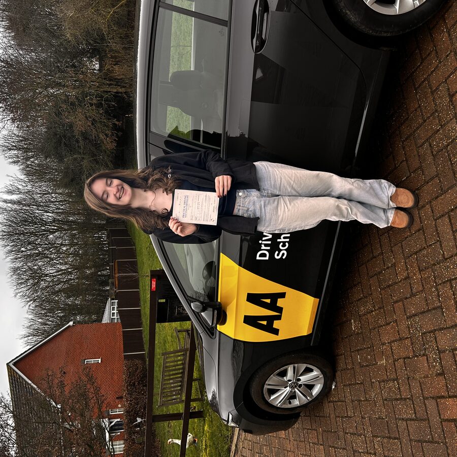 Abbie holding her practical driving test pass certificate