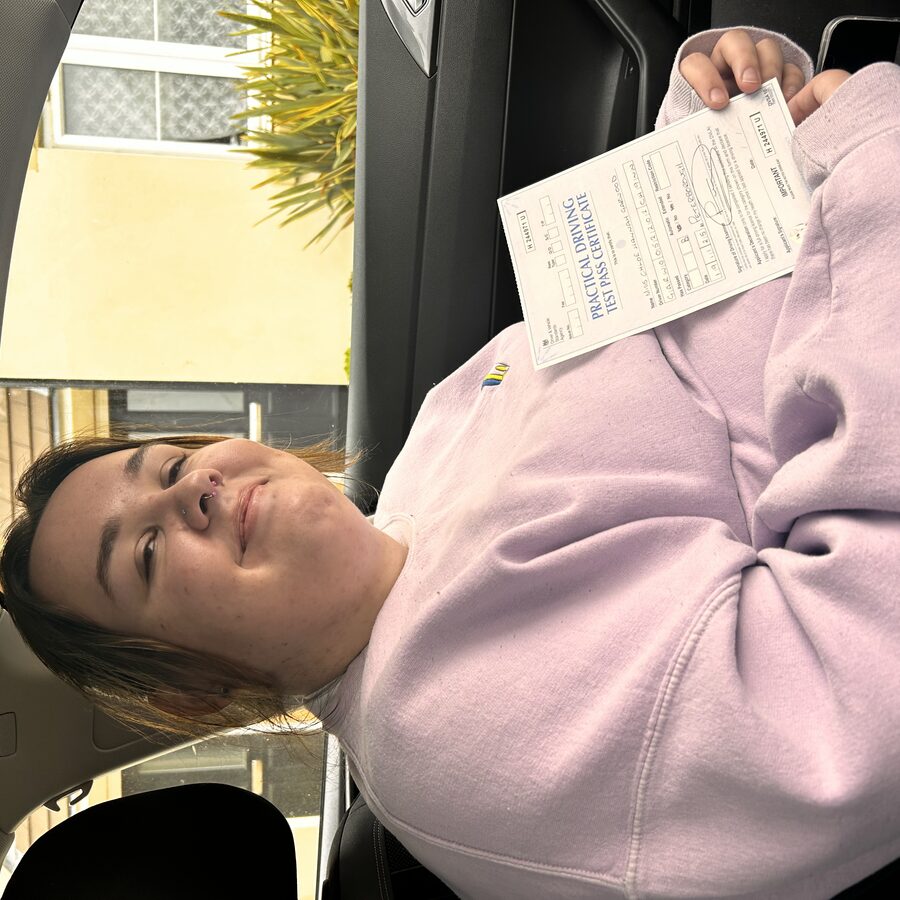 Chloe holding her practical driving test pass certificate